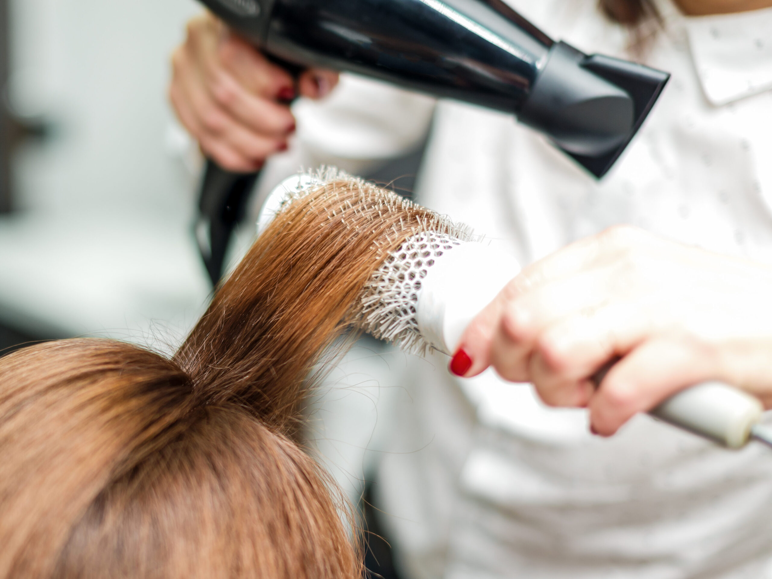 Professional hairdresser dries hair with hairdryer. Close-up of hair dryer, concept barber salon, female stylist.