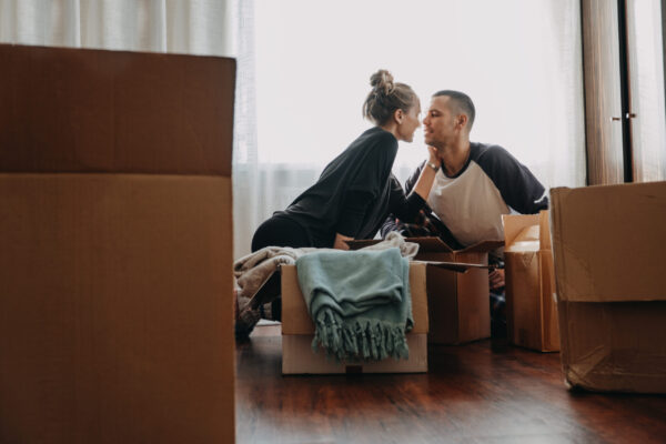 Moving Day, new home, Valentine's Day, unpacking boxes, newlyweds concept. Happy couple is having fun with cardboard boxes in new house.