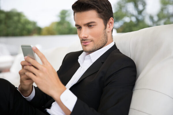 Portrait of a handsome man using smartphone outdoors in restaurant