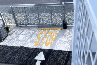 Yellow stop sign on textured ground under sunlight.