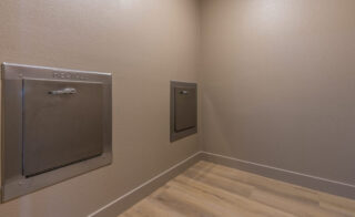 Empty room with recycle chute on wall.