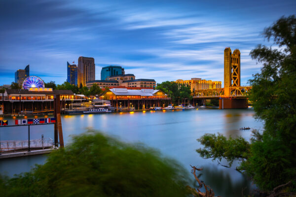 Gold Tower Bridge and Sacramento River in Sacramento, California, photographed from River Walk Park at night.