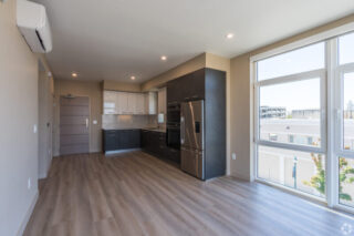 Modern, empty apartment kitchen with large windows.