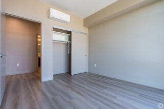 Empty room with wood flooring and closet doors.
