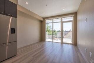 Bright empty room with large windows and wooden floor.