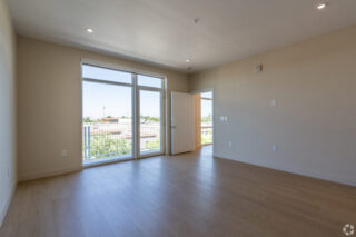 Spacious empty room with wooden floor and large window.