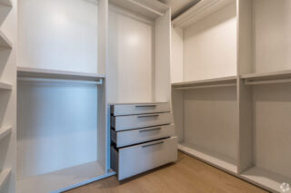 Modern walk-in closet with open shelving and drawers.