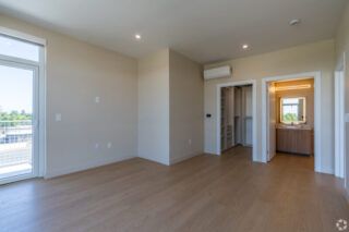 Empty room with wood floors and open closet.