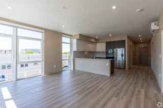 Modern kitchen with large windows and wooden floors.